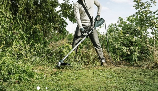 Un travailleur utilisant le coupe-bordure Bosch AFS 23-37 dans des herbes hautes