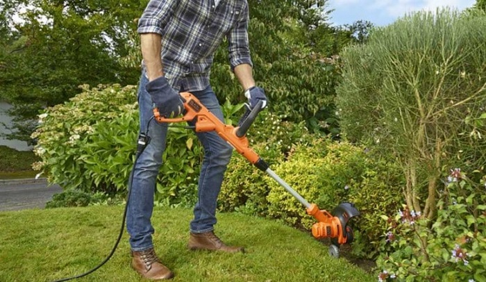 particulier qui utilise le coupe-bordure BLACK et DECKER BESTA530C10-QS pour dresser la limite d'un massif de fleure